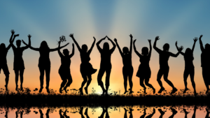 People jumping happily are silhouetted against the backdrop of a sunrise or sunset.