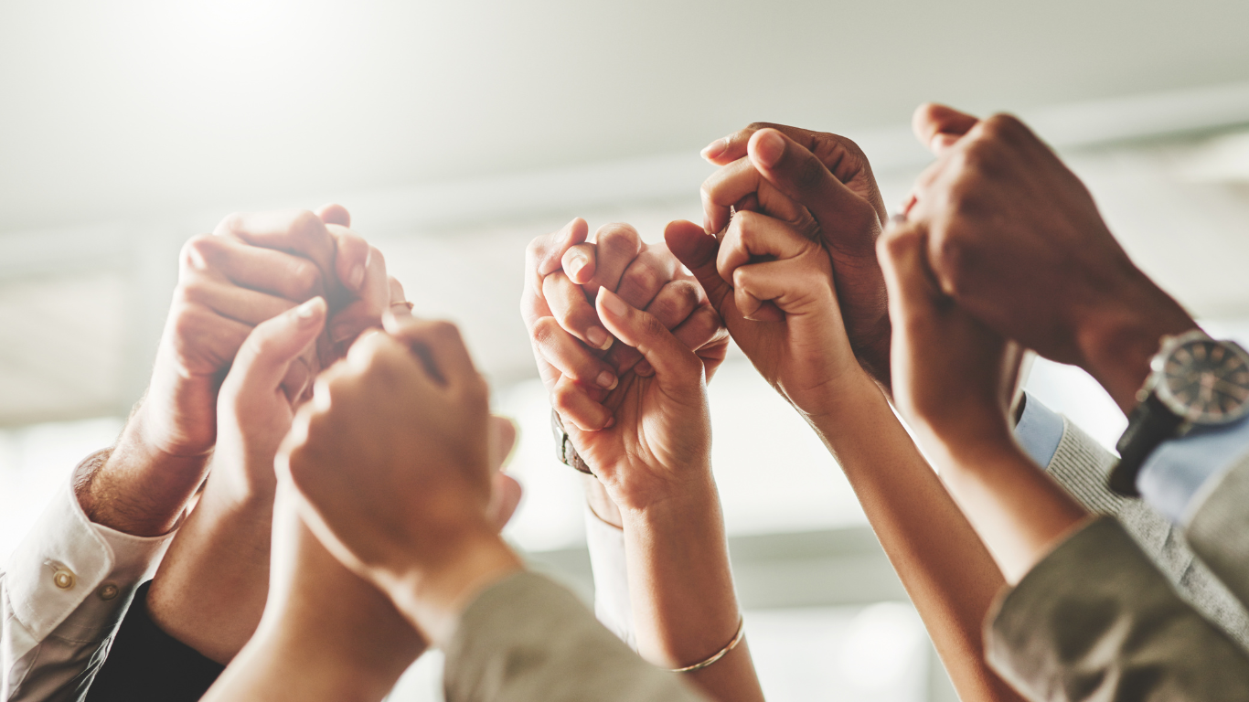 People's hands clasped together and raised in the air.