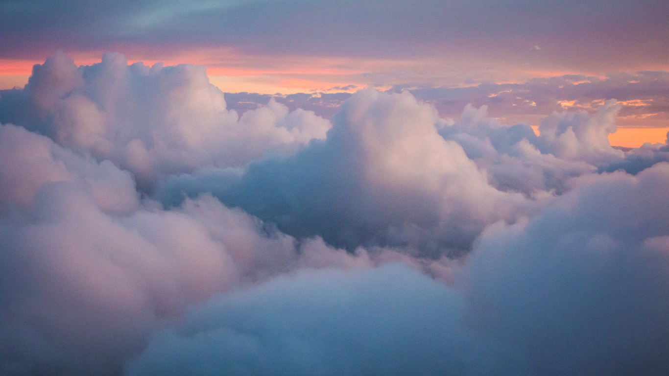Fluffy clouds against a backdrop of dusk, seen from thousands of feet in the air.